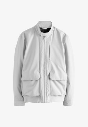 Hellgraue Jacke mit hohem Kragen, Reißverschluss vorne und zwei großen Klappentaschen. Glattes Material mit elastischen Bündchen und Saum.