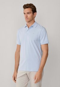 Lichtblauw poloshirt met een klassieke kraag, korte mouwen en een subtiel logo op de borst. Gemaakt van gladde stof, aansluitend model.
