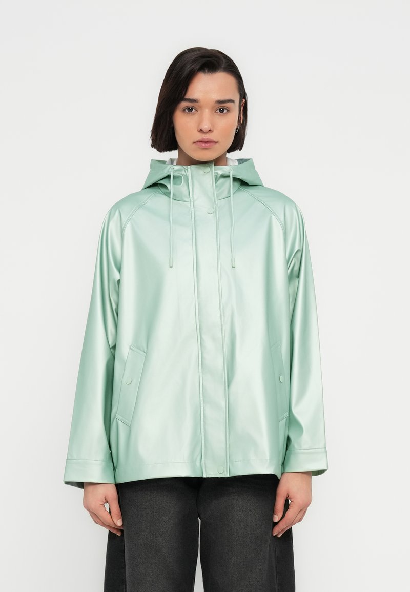 Πράσινο μέντας αδιάβροχο μπουφάν με γυαλιστερή επιφάνεια και κουκούλα. Διαθέτει φερμουάρ μπροστά, δύο πλαϊνές τσέπες και ρυθμιζόμενα κορδόνια. Λείο υλικό.