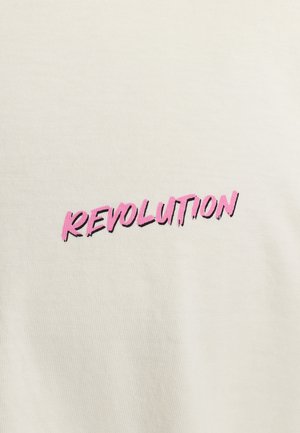 Crèmekleurig t-shirt met gedurfde, roze bedrukte tekst die "REVOLUTION" zegt, met een verouderde uitstraling. Gemaakt van zacht katoen.
