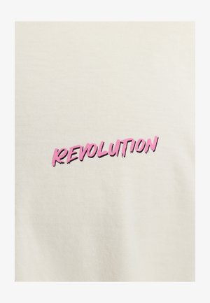 Crèmekleurig t-shirt met gedurfde, roze bedrukte tekst die "REVOLUTION" zegt, met een verouderde uitstraling. Gemaakt van zacht katoen.