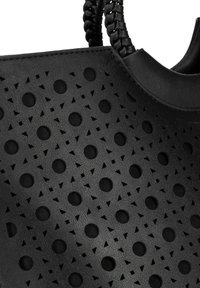 Zwarte tote bag gemaakt van textuurmateriaal met uitsnijdingen, voorzien van cirkelvormige en driehoekige vormen; gebreide handgreepaccenten.