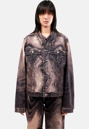 Veste en denim avec un motif abstrait texturé dans des tons de brun et de noir. Elle présente une fermeture à boutons, deux poches avant et un col classique.