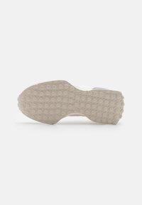 Suola della scarpa realizzata in un materiale gommato beige chiaro con una texture e schemi di grip circolari; bordi lisci che si assottigliano verso il tallone.