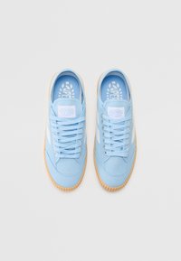 Light blue canvas sneakers with a round toe, lace-up front, rubber sole, and a textured brown outsole. Includes branding on the insole.
