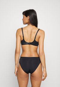 Crni bikini set koji uključuje bralet s podešivim trakama i kopčanjem, uparen s visokim badićem. Glatka tekstura.
