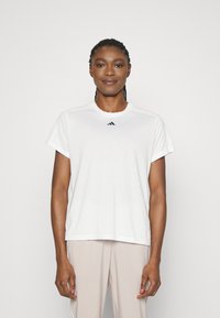 Biely krátky rukáv tričko vyrobené z mäkkého materiálu, s okrúhlym výstrihom a malým čiernym logom Adidas umiestneným na hrudi.
