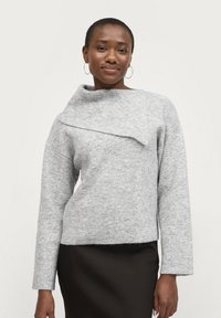 Helles graues Strickpullover mit umgeschlagenem Kragen, langen Ärmeln, abgerundetem Saum und weicher Textur, kombiniert mit einem dunklen Rock.