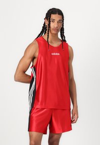 Red athletic tank top and shorts set made of shiny material. Features black side stripes with white accents and an Adidas logo on the chest.