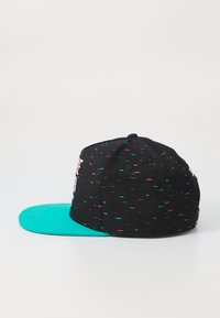 Svart baseballcap med en turkise skygge, prydet med spredte røde og blå abstrakte mønstre samt broderte tekster på frontpanelet.