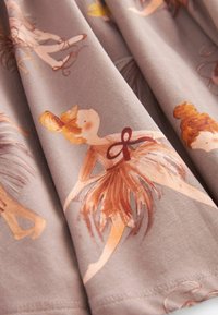 Svetlohnedá bavlnená látka s hravými ilustráciami baletných tanečníc v jemných pastelových odtieňoch. Dizajn zahŕňa splývavé sukne tutu a vlasové doplnky.