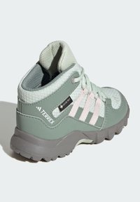 Terrex matkajalatsid, millel on piparmündiroheline võrkkangas ja sünteetiline ülemine osa, roosa detailidega, tekstuurse välispohjaga ja veekindel Gore-Tex silt.