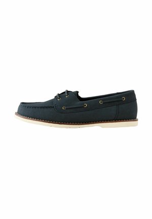 Navy blue boat shoe made of leather, featuring a smooth texture, stitched detailing, gold-tone eyelets, and a white rubber sole.