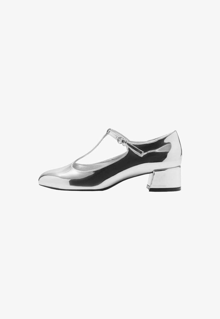 Silver patent leather Mary Jane shoe with a rounded toe, clear side panel, and a mid-height block heel. Thin ankle strap with a buckle.