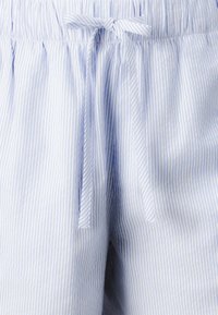 Pantaloni corti a righe blu e bianche in tessuto morbido, con cintura elastica e un nodo frontale, caratterizzati da una vestibilità rilassata e una leggera lucentezza.