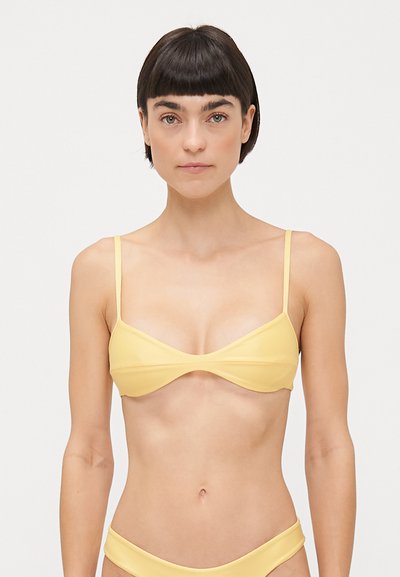 Top di bikini giallo con spalline sottili, forma triangolare e tessuto morbido. Cuciture delicate lungo i bordi e design minimalista.