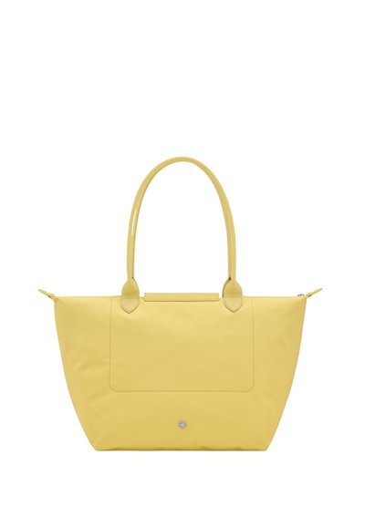 Yellow tote handbag with long handles, a front patch pocket, and a small round metal stud near the bottom center.
