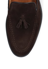 Ciemnobrązowe zamszowe mokasyny z podwójnymi zdobieniami z frędzlami, widocznym przeszyciem wzdłuż krawędzi oraz gładkim skórzanym wnętrzem. Klasyczny fason mokasyn.