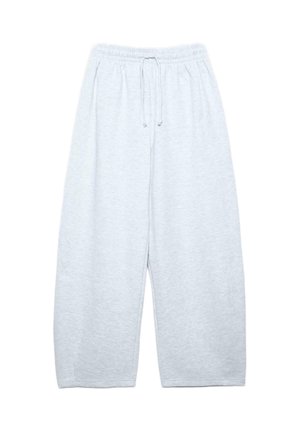 Osoba nosząca szary prążkowany top z długim rękawem, oversize jasnoszare spodnie dresowe, czarne buty oraz niebieski sweter zarzucony na ramiona.