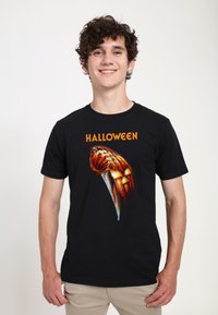 Černé tričko s motivem Halloweenu: design s nožem a vyřezávanou dýní s oranžovými akcenty, krátké rukávy a kulatý výstřih.