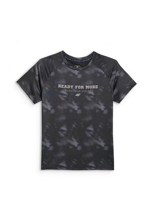 Chłopiec stoi prosto, ubrany w czarną koszulkę tie-dye z tekstem "Ready for More", czarne szorty, białe skarpetki w paski i czarno-białe trampki.