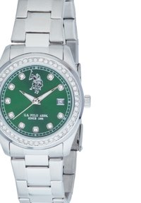 Montre en métal argenté avec un cadran vert, accents en cristal sur la lunette et index des heures argentés. Les caractéristiques incluent une fenêtre de date et un bracelet en maillons poli.