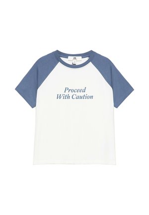 T-shirt blanc à manches courtes avec des manches raglan bleues et la phrase "Proceed With Caution" imprimée à l'avant en texte bleu.