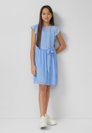 Robe bleu clair avec manches courtes volantées, jupe plissée et ceinture nouée à la taille. Associée à des baskets blanches. Design simple.