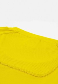 Prenda de manga corta amarilla con una textura suave y un escote redondeado, con un detalle de costura horizontal en el hombro y la espalda.