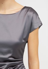 Robe en satin gris avec un large décolleté en forme de cœur et des manches courtes; texture lisse, coupe ajustée, et détail froncé à la taille.