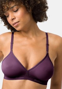 Purple bralette with a triangular cup design, adjustable straps, and a soft fabric texture. Elastic band features subtle logo detail.