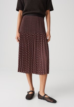 Textured mid-length skirt in burgundy with a geometric pattern in cream and black, paired with black mesh flats featuring a strap detail.