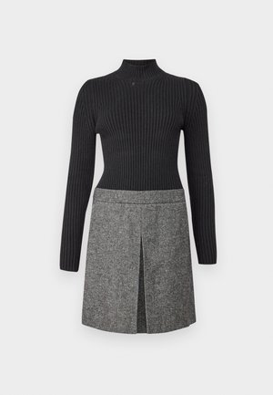 Knitted black turtleneck with ribbed texture paired with a gray woven skirt featuring a front slit and subtle pattern details.