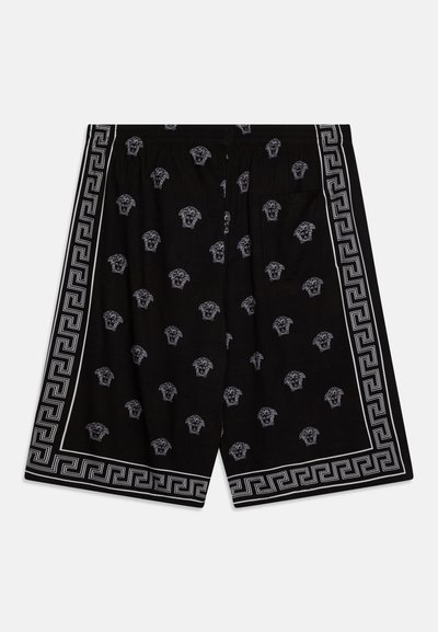 Černé šortky s celoplošným opakujícím se vzorem bílých medailonů, obroubené kontrastním geometrickým lemem. Elastický pás.