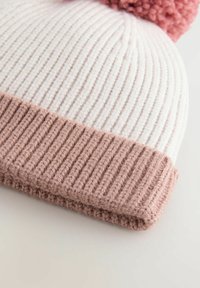 Strickmütze mit einem weißen gerippten Oberteil, leicht rosa umgeklapptem Bündchen und einem strukturierten rosa Pompon oben. Weiches Garn mit einer gemütlichen Erscheinung.