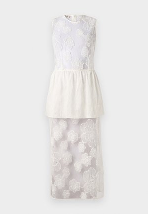 Robe blanche avec un haut sans manches mettant en valeur une broderie florale, une taille en peplum superposée et une jupe inférieure transparente ornée de motifs floraux.