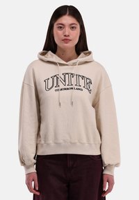 Beige hoodie met de tekst "UNITE TOMORROW LAND" in zwart. Kenmerken zijn geribbelde manchetten en zoom, een ontspannen pasvorm en een zachte textuur.