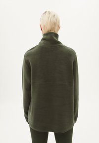 Pullover in pile verde scuro con colletto alto, caratterizzato da una vestibilità comoda, una texture liscia e una cucitura orizzontale sulla schiena.