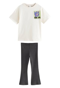 T-shirt crème à manches courtes avec un motif graphique coloré et leggings évasés côtelés noirs, tous deux fabriqués en tissu doux et léger.