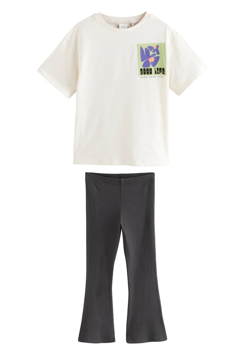 T-shirt crème à manches courtes avec un motif graphique coloré et leggings évasés côtelés noirs, tous deux fabriqués en tissu doux et léger.