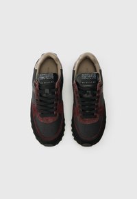 Sneakers featuring a mix of black fabric and burgundy suede, padded collar, textured rubber sole, and black laces with printed labels on the tongue.