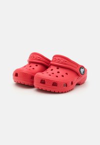Red plastic clogs with ventilation holes, a back strap, and textured sole. Features embossed logo on the side and rounded toe design.