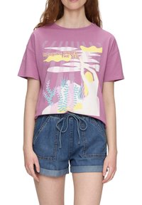 Hellblaues Baumwoll-T-Shirt mit einem grafischen Druck, der den Text "Morgen unter dem Meer" und bunte Unterwasser-Elemente zeigt. Kombiniert mit Jeansshorts.