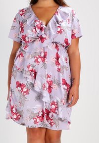 Kevätmekko vaaleanlaventelin värissä, jossa on punaisia ja valkoisia kukkia. Mekossa on röyhelöhiha ja -helma, v-aukko ja kerroksellinen röyhelöyksityiskohta vyötäröllä.