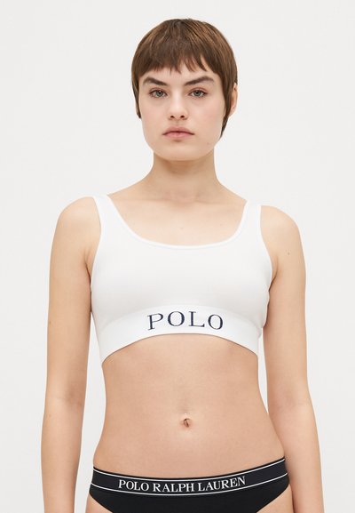 Bijela rebrasta bralette s širokim mornarsko plavim remenom na kojem se nalazi "POLO" logo. Podesive naramenice i jednostavan, minimalistički dizajn.