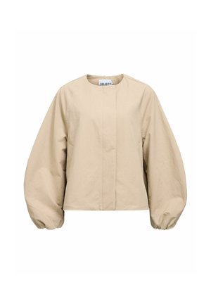 Veste beige à manches longues avec manches ballon surdimensionnées, col rond et fermeture à boutons sur le devant, étiquetée "OBJECT" à l'intérieur du col.