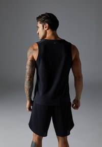Black athletic tank top and shorts, featuring a loose fit, smooth texture, and breathable fabric. The shirt has no designs, and the shorts are slightly longer.