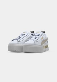 Weiße synthetische Sneaker mit einer dicken grauen Plattformsohle. Besitzt goldene Akzente und ein Logo auf der Zunge. Schnürdesign mit strukturiertem Finish.