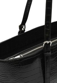 Črna torbica s krokodiljim vzorcem, gladke teksture, z zadrgo in nastavljivim naramnim trakom. Pologna kovinska okrasja.