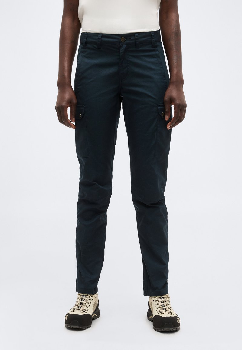 Person wearing dark navy cargo pants and beige hiking shoes against a plain light background.